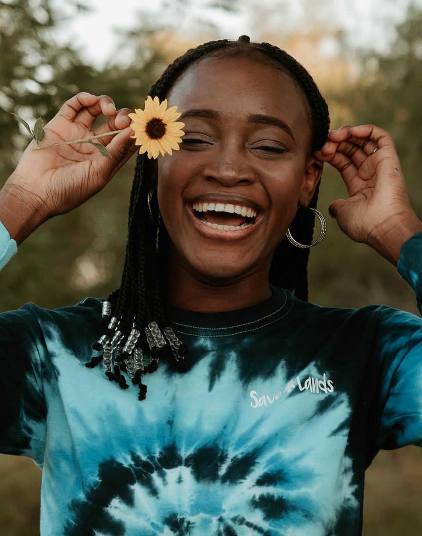 woman holds a flower in her hair in a park